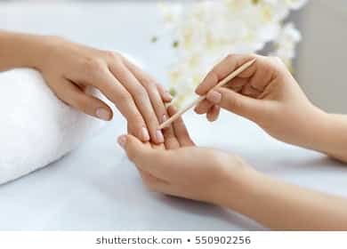 Mujer limpiando cutículas de su clienta